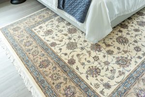A cream and blue oriental rug beneath a bed to illustrate David Tiftickjian And Son's professional rug cleaning services.