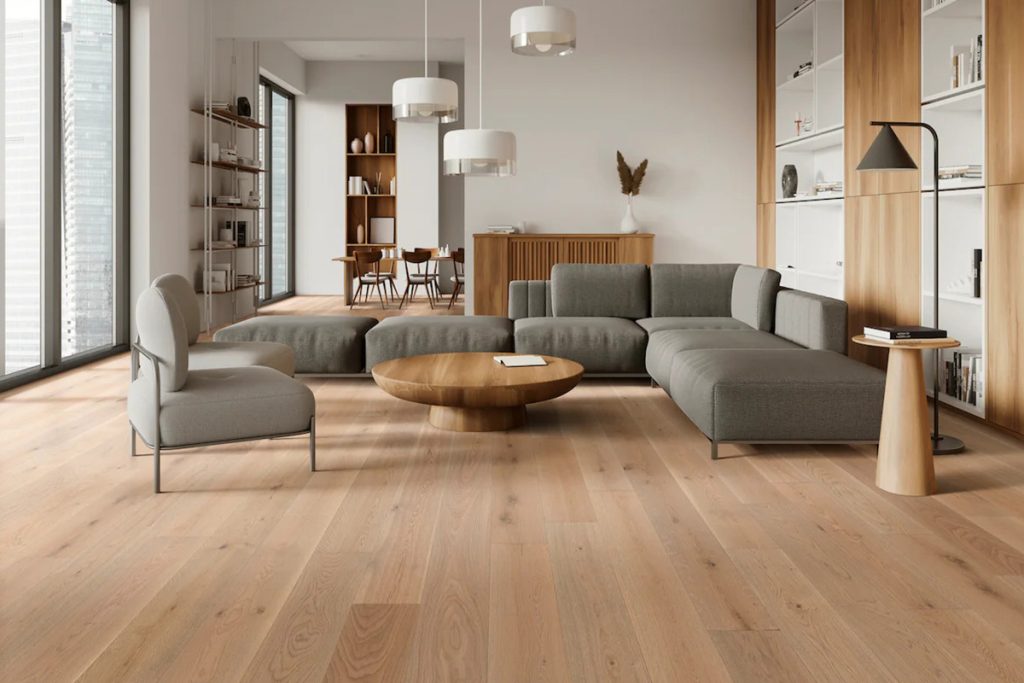 A bright living room with a gray couch and wide-plank wood floor – a 2026 floor trend.