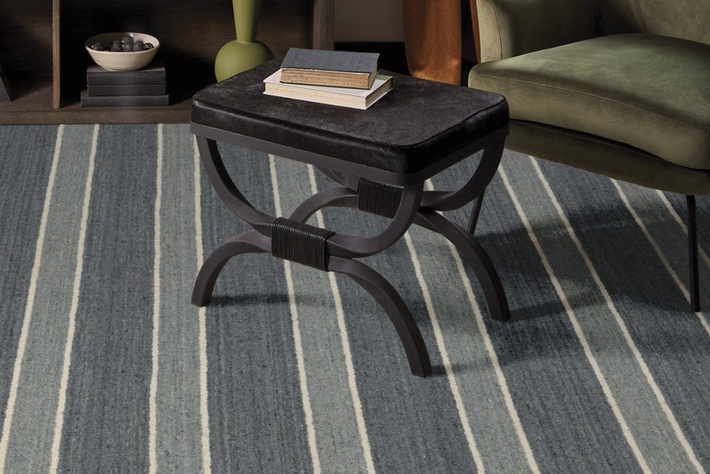 A black table and green chair on blue striped broadloom carpet.