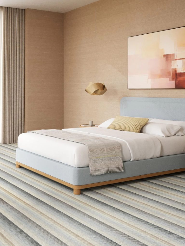 Multicolored striped carpet beneath a blue and white bed.