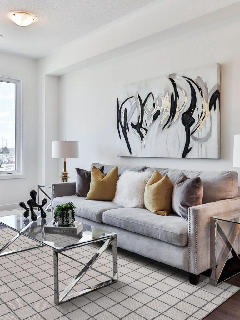 A light checkered carpet by Prestige Mills under a a gray couch and glass table.