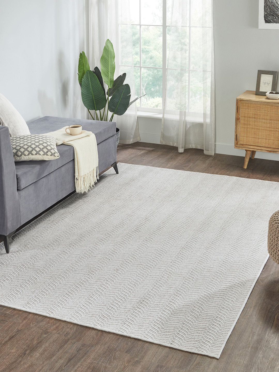 Light gray carpet by Prestige Mills with a dark sofa and green houseplant.