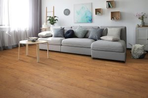 Warm hardwood flooring with a gray sofa and a living room setting.