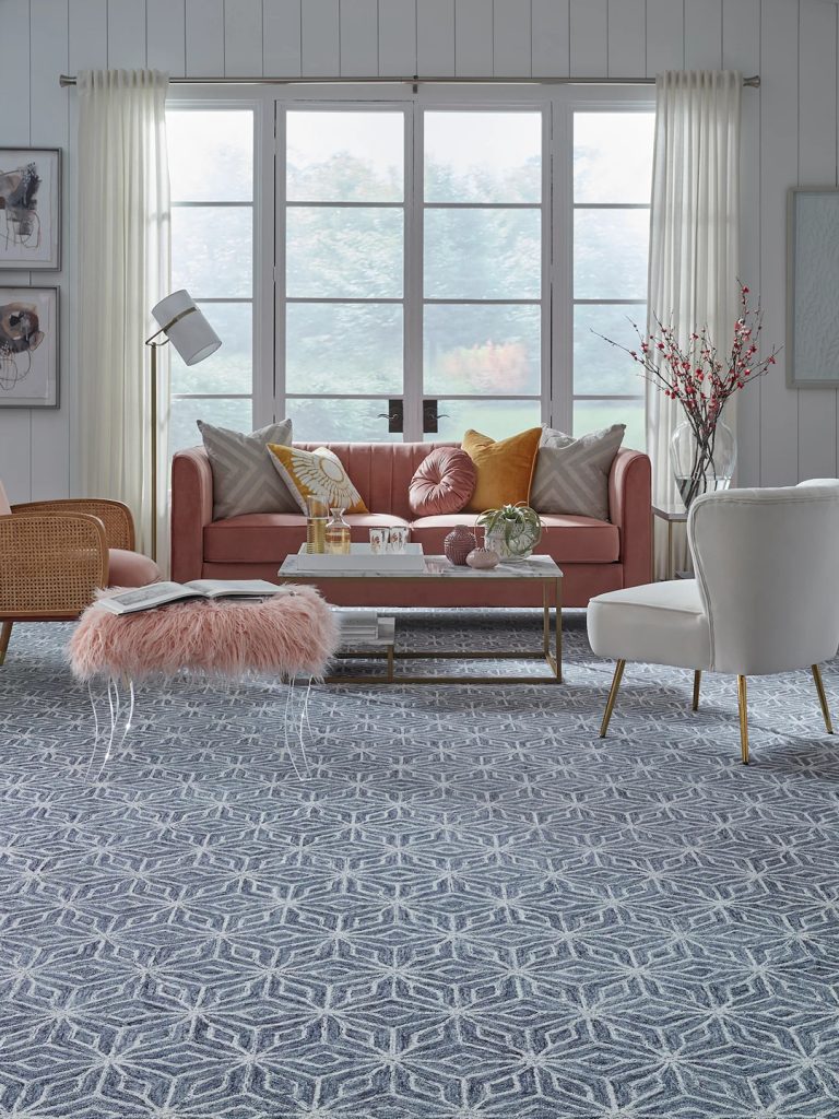 Blue and white patterned carpet with light colored furniture in front of a large window.