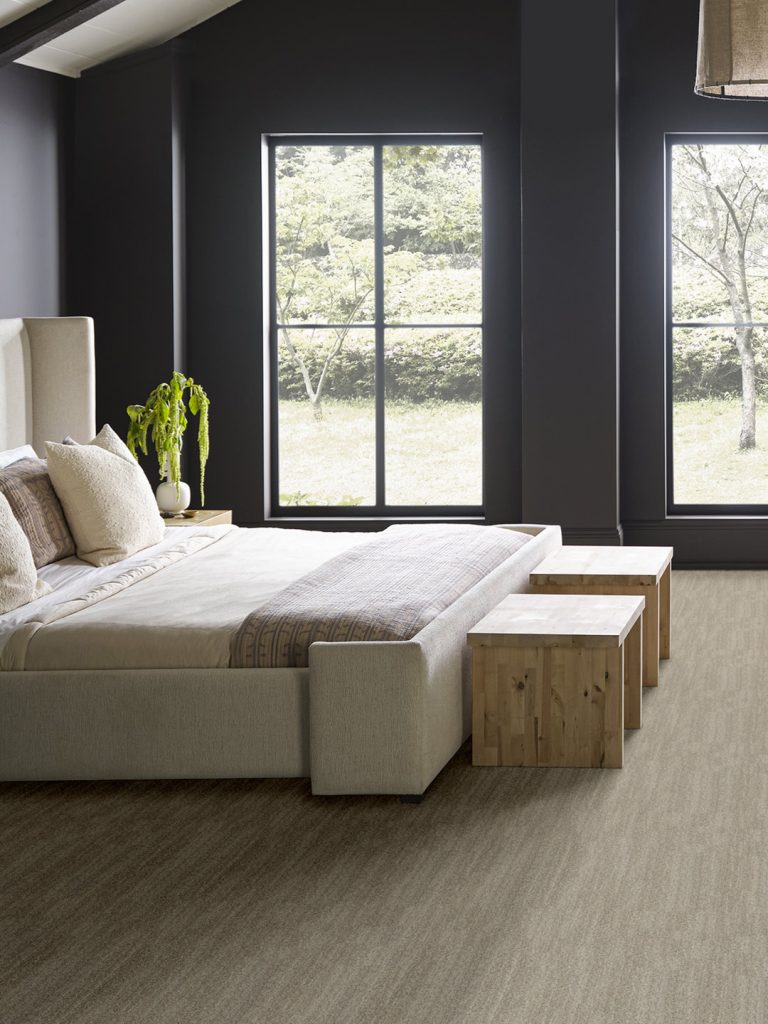 Light brown carpet with a white bed and navy walls for our spring carpet inspo.