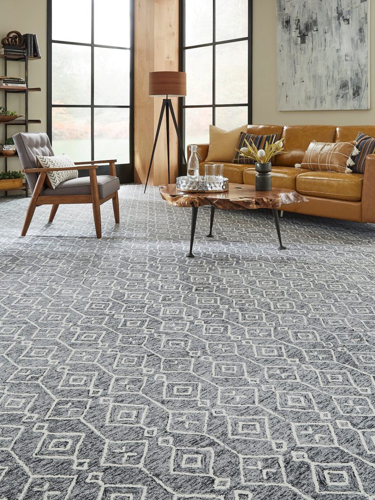 A dark gray and white patterned carpet with yellow and wood furniture for our spring carpet inspo.