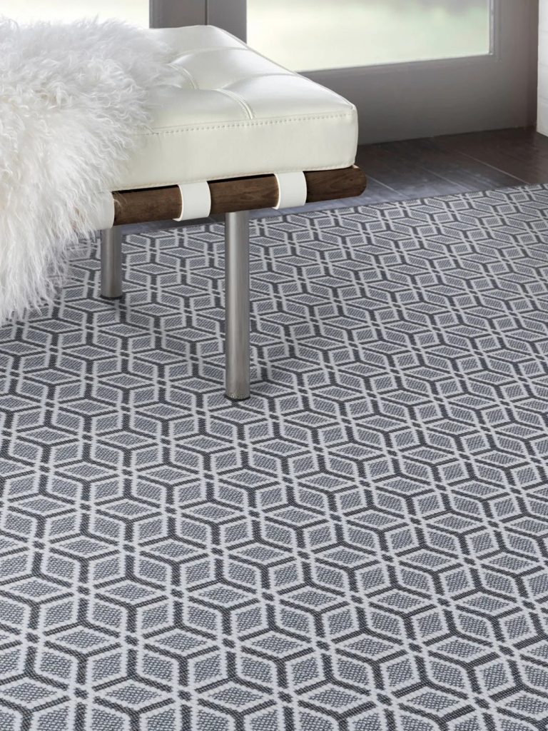 A blue geometric carpet with a white bench.