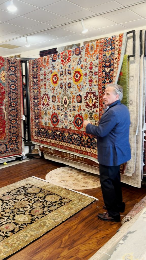 Dave Tiftickjian showing a rack of oriental rugs. 