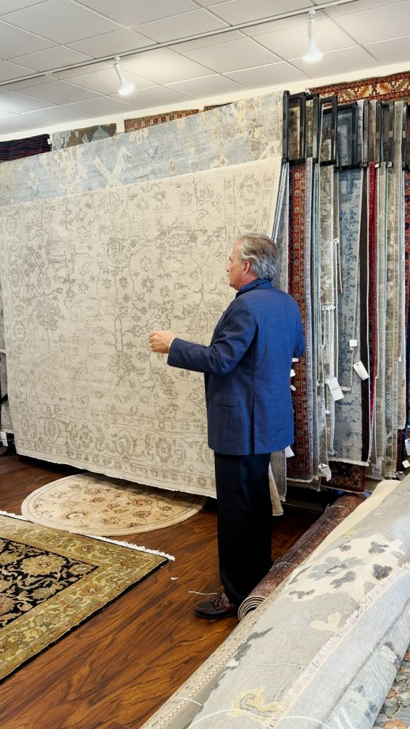 Dave Tiftickjian showing a rack of oriental rugs.