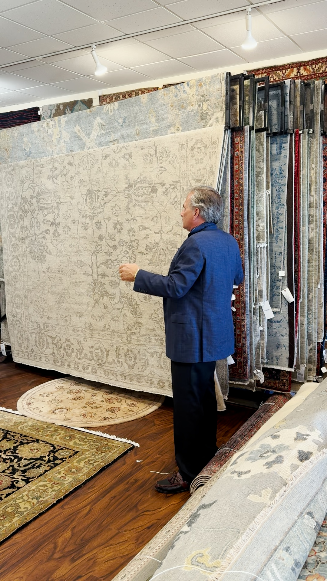 Dave Tiftickjian showing a rack of oriental rugs.