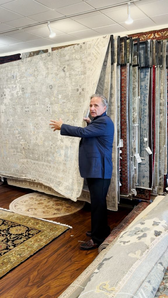 Dave Tiftickjian showing a rack of oriental rugs.