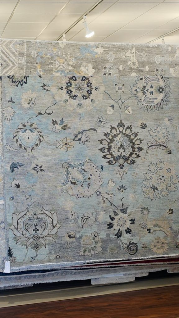 Blue and gray oriental rug hanging on a rack.