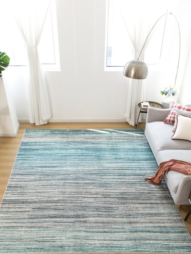 A light blue to gray ombre machine-made rug in a living room setting.