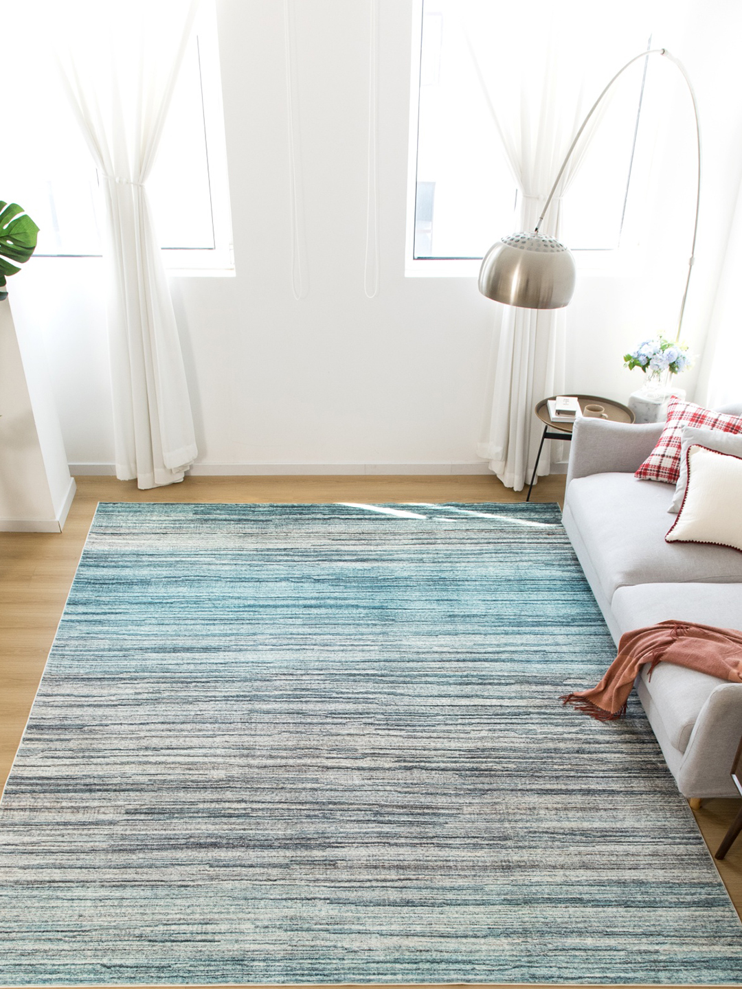 A light blue to gray ombre machine-made rug in a living room setting.