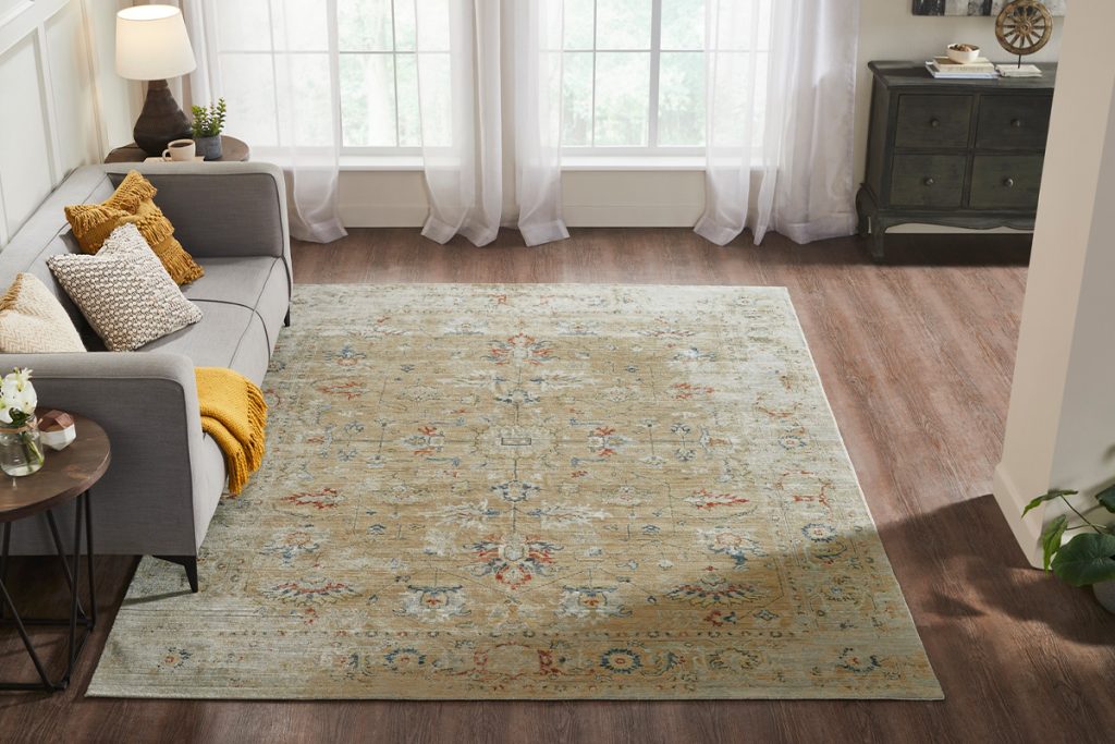 A gold machine-made rug with a blue and red oriental pattern in a living room setting.