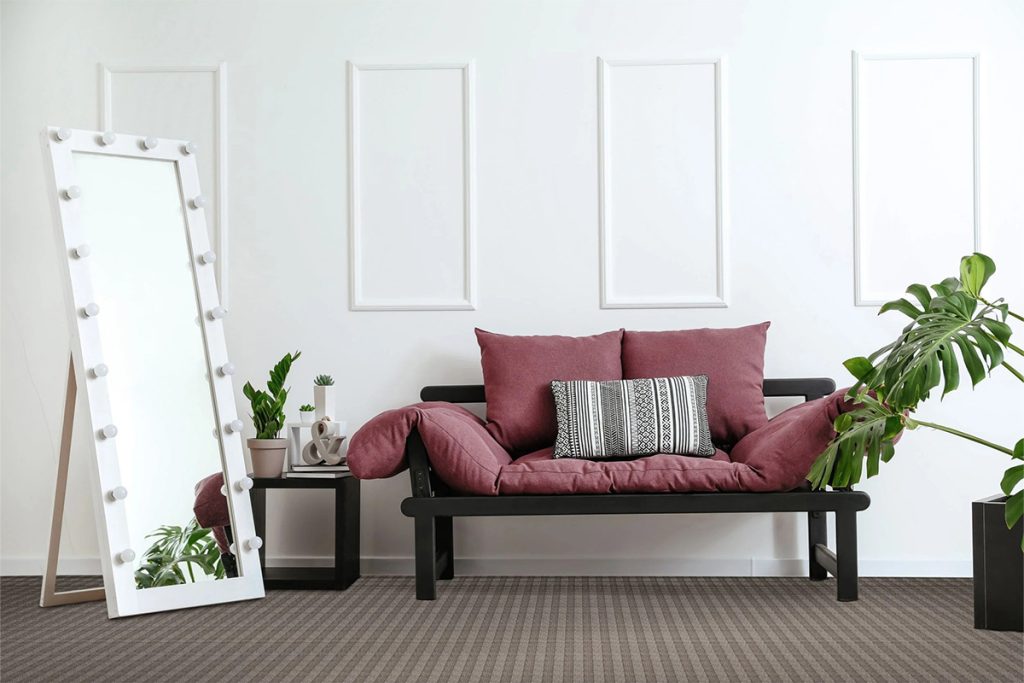 A dark brown striped residential carpet beneath a dark bench with dark red cushions beside a potted plant.