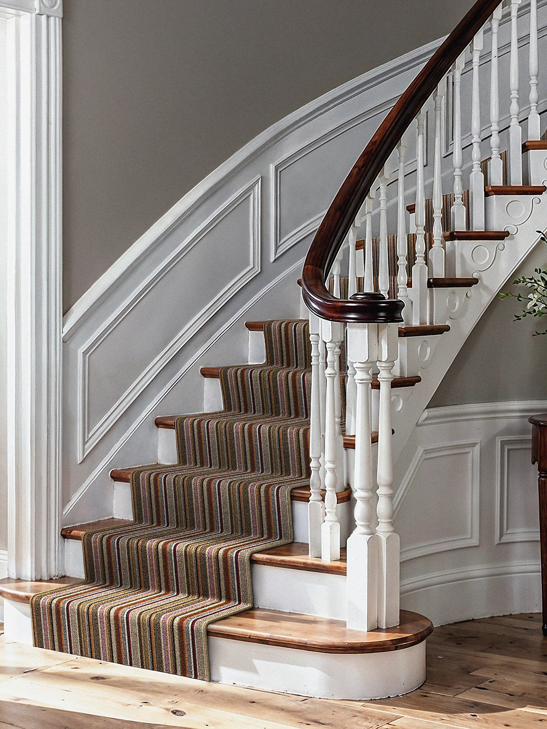 A neutral, multicolored striped carpet going up a staircase.