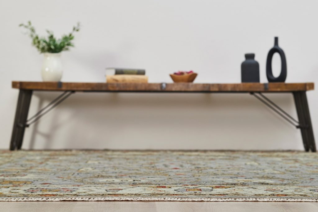 Side view of an oriental rug with a bench blurred in the background. Highlighting our Summer Rug Sale.