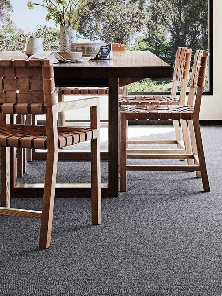 A dark grey rug beneath a wood dining table and chairs.