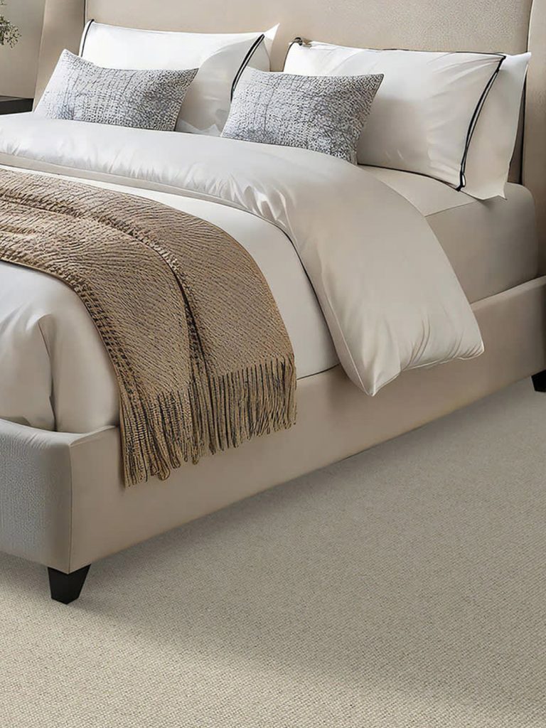 Light colored wool carpet with a large, white and beige bed.