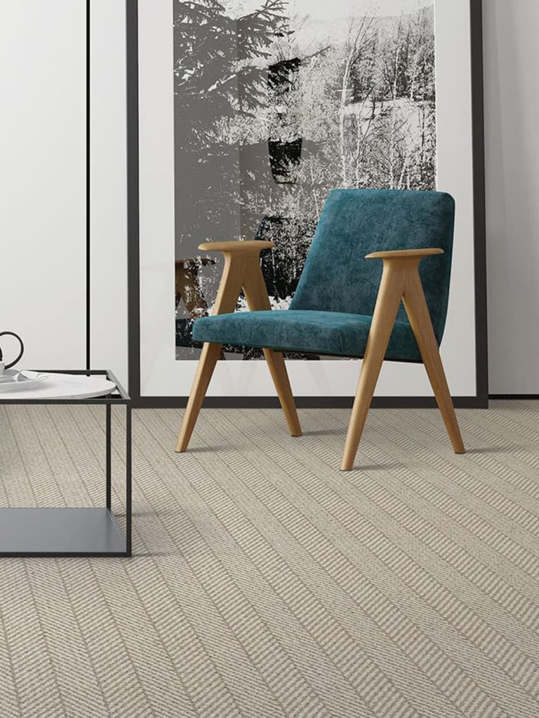 A beige patterned carpet with a teal chair and large black and white abstract photo.
