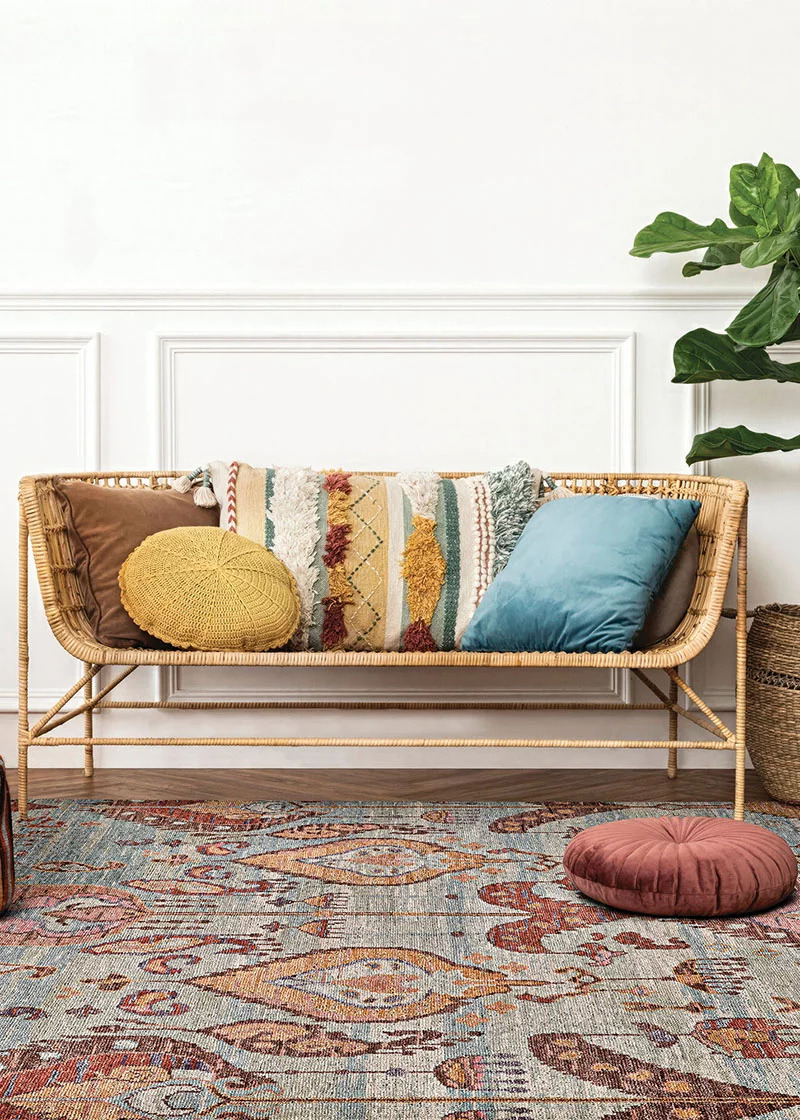 A brightly colored, traditional style rug beneath a sofa to advertise our Couristan rug and carpet sale.