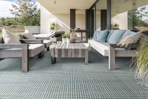A blue patterned outdoor carpet with a living room setting to advertise our Couristan rug and carpet sale.