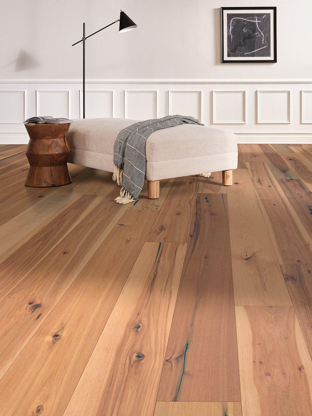 Alternating shades of light brown and medium brown hardwood flooring with a white lounge couch.