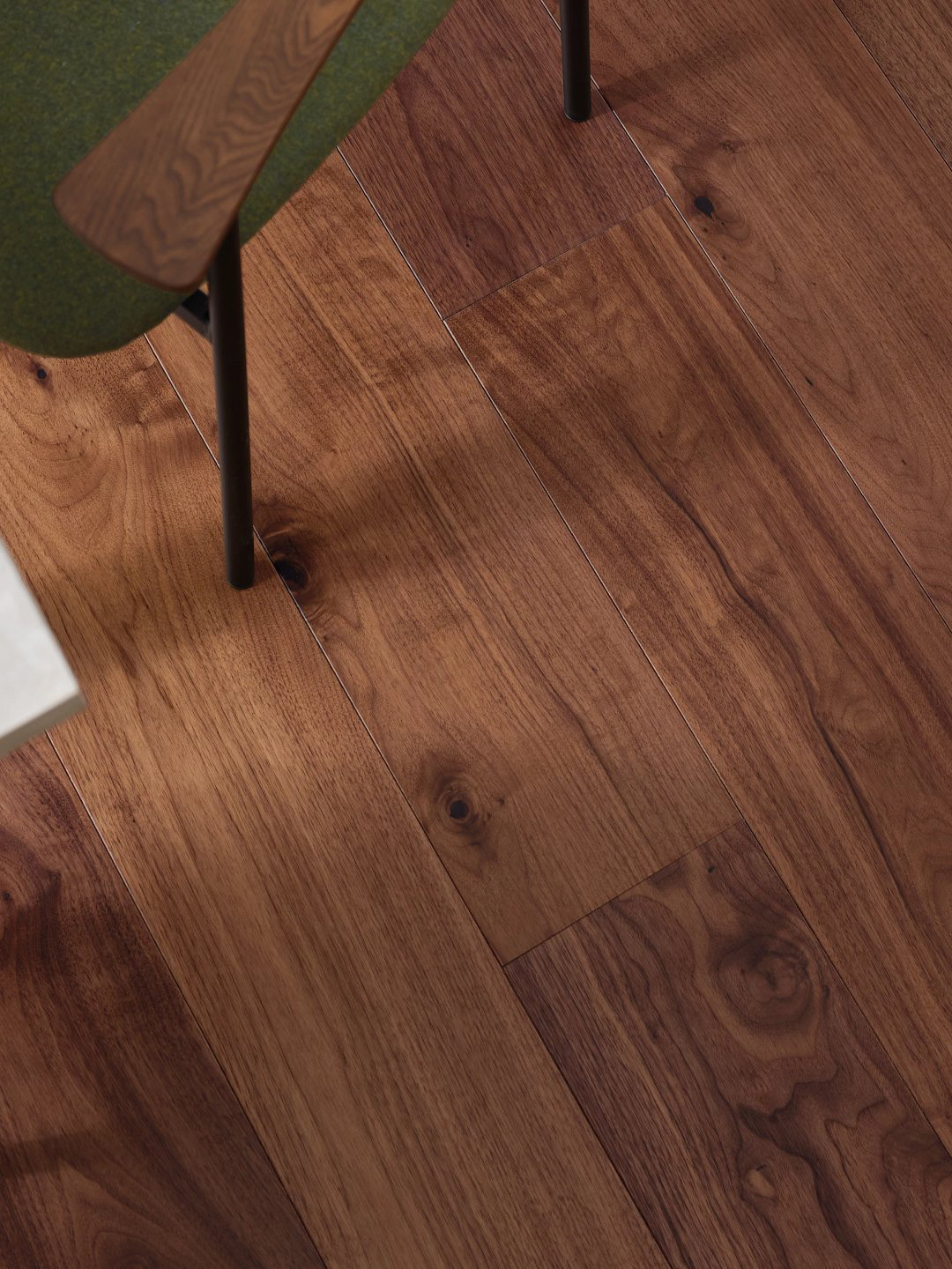 Overview of a dark hardwood floor with a green chair leg.