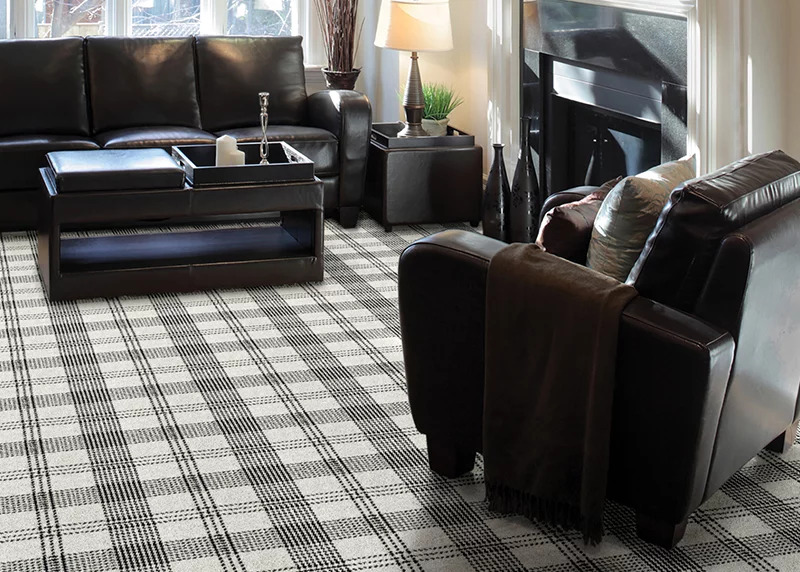A plaid broadloom carpet in a living room setting with black leather furniture.