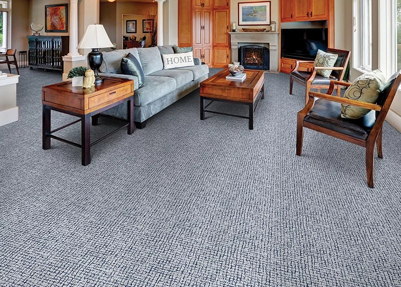 A blue textured broadloom carpet in a living room setting with natural wood walls and furniture.