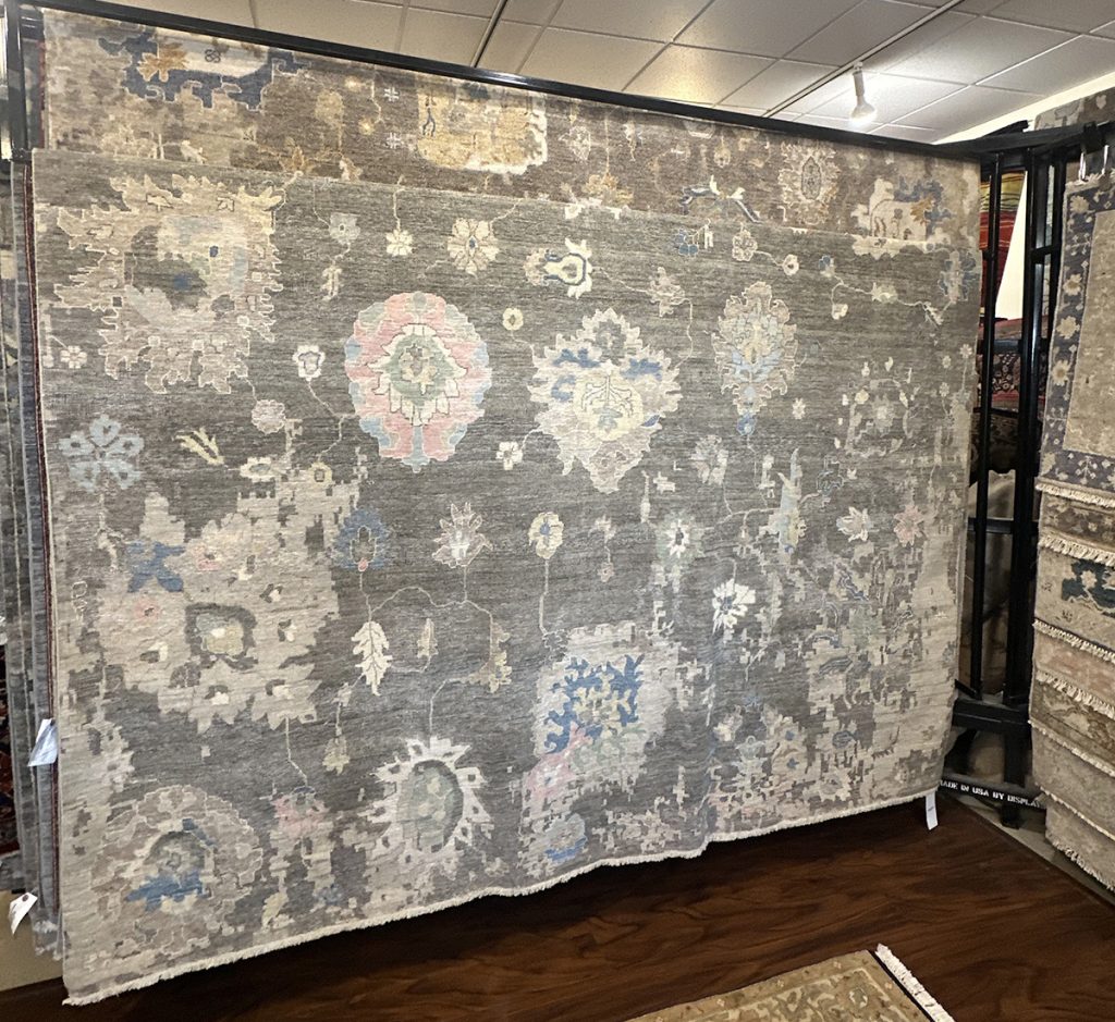 One of our 9'x12' oriental rugs which features a gray background and a transitional/traditional design.