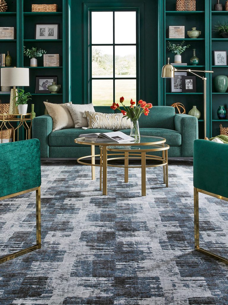 An abstract blue and gray patterned Masland carpet in a living room setting with teal built-ins and furniture.
