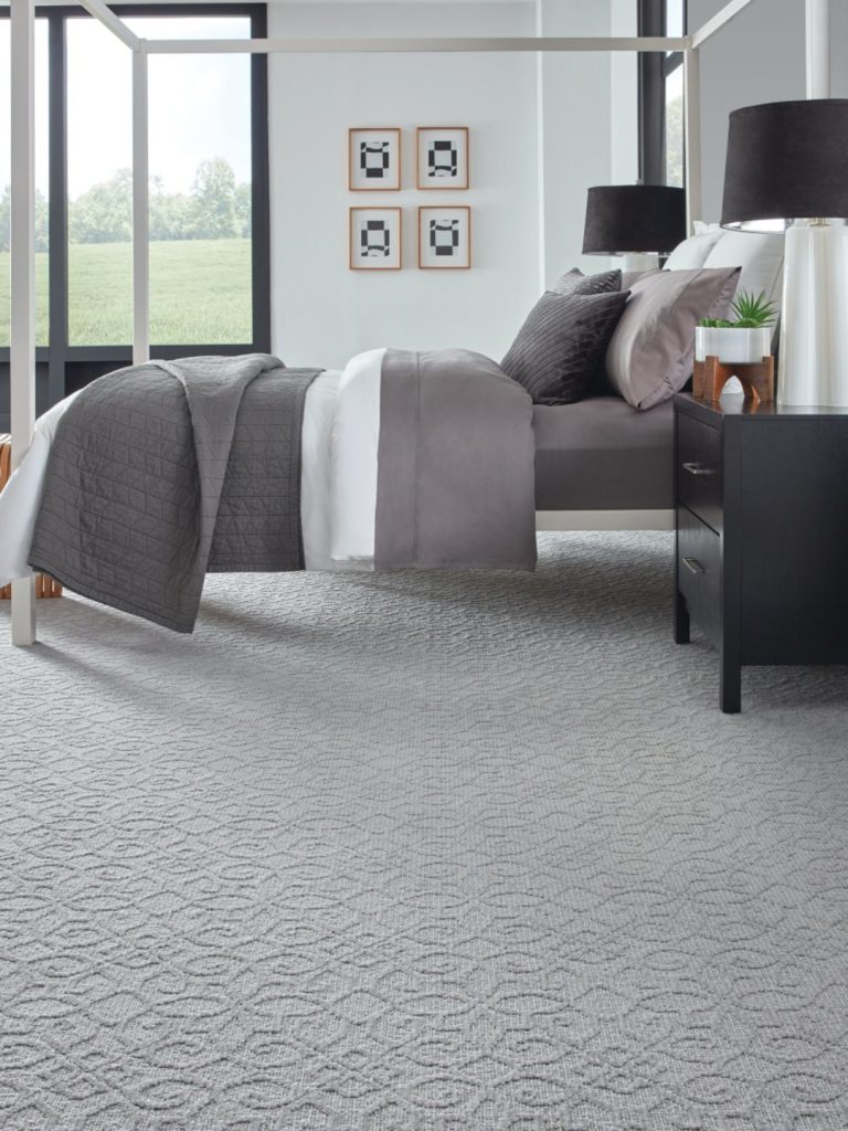 A gray carpet by Masland with subtle curvy medallion tiles in a bedroom setting 