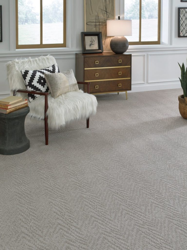 A chevron inspired carpet by Masland inwith a white fuzzy chair and wood cabinet